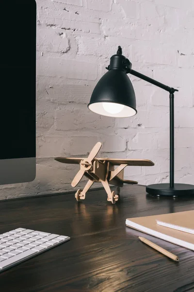 Close-up view of desktop computer with black screen and wooden plane at workplace — Stock Photo