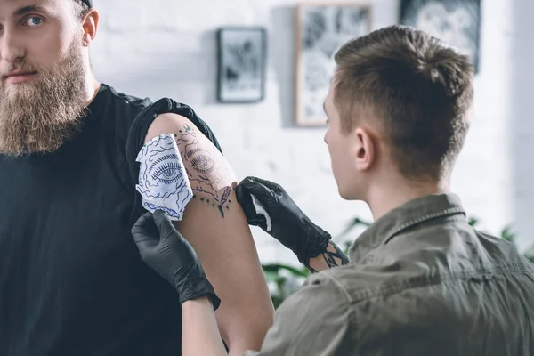 Tattoo artist in gloves working on shoulder piece sketch in studio — Stock Photo