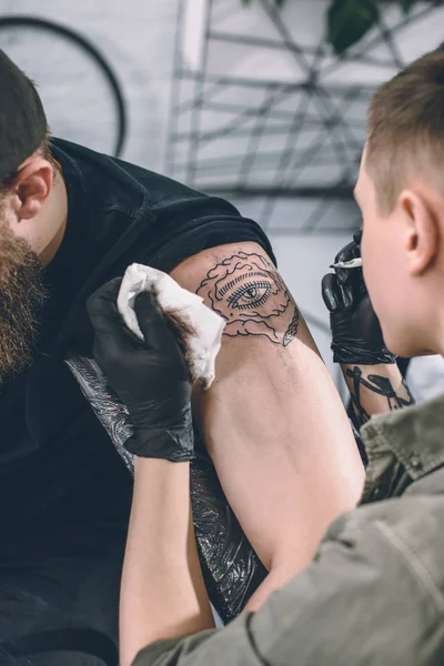 Tatuaje artista trabajando en hombro pieza en estudio - foto de stock