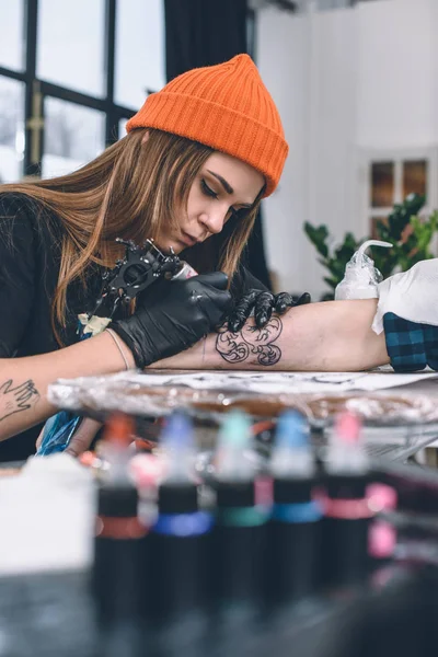 Donna che crea tatuaggio sul braccio maschile — Foto stock
