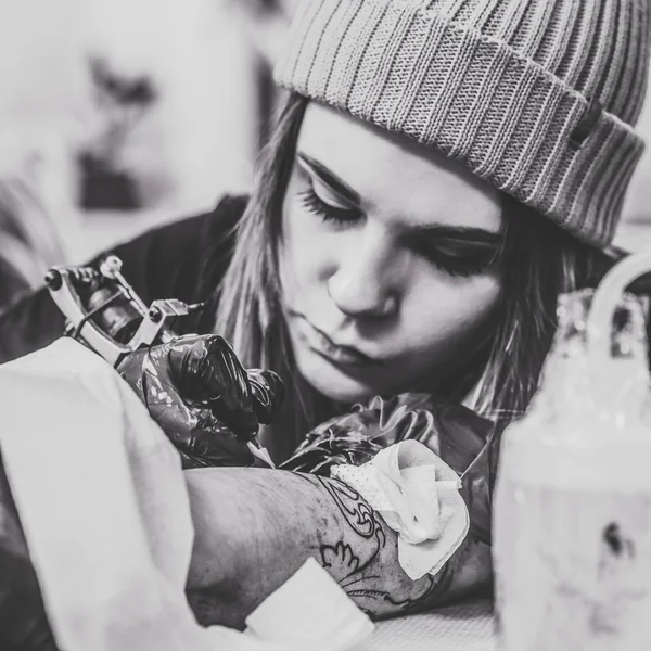 Чорно-біла фотографія майстра татуювання жінки під час татуювання в студії — стокове фото