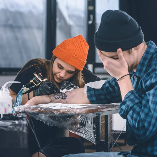 Mann erträgt Schmerzen während Tätowierungsprozess im Studio — Stockfoto