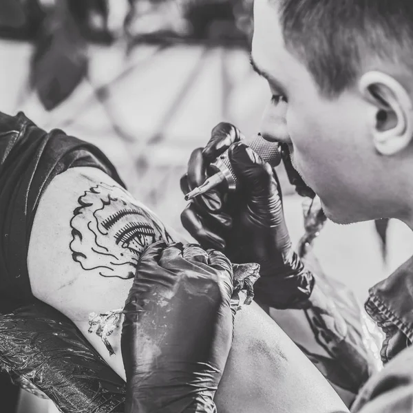 Foto en blanco y negro del maestro del tatuaje trabajando en la pieza del hombro en el estudio - foto de stock