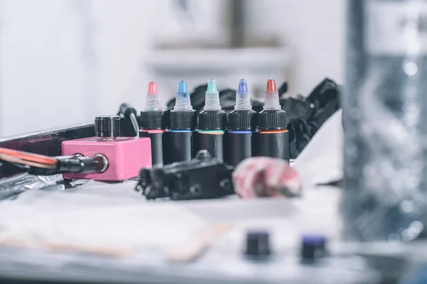 Máquina de tatuaje y botellas con tinta de colores - foto de stock