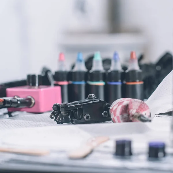 Lieu de travail de tatoueur avec machine et bouteilles avec encre de tatouage colorée — Photo de stock