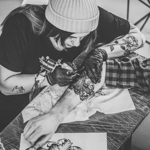 Foto in bianco e nero di donna tattoo master e uomo durante il processo di tatuaggio in studio — Foto stock