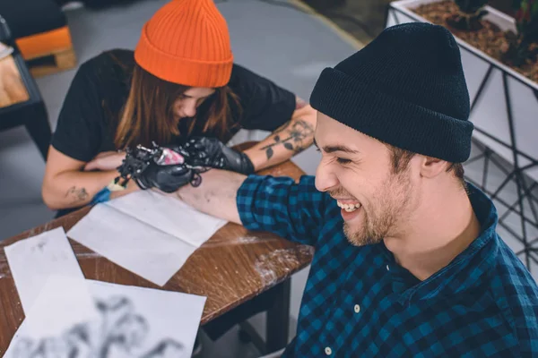 Man enduring pain during tattooing process in studio — Stock Photo