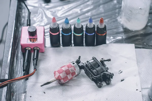 Lieu de travail de tatoueur avec machine et bouteilles avec encre de tatouage colorée — Photo de stock