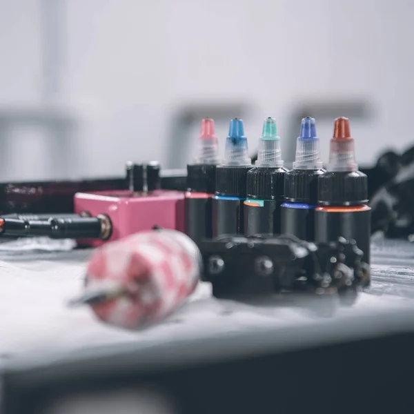 Tattoo machine and bottles with colorful ink — Stock Photo