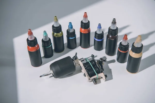 Bottles with colorful tattoo ink and machine — Stock Photo