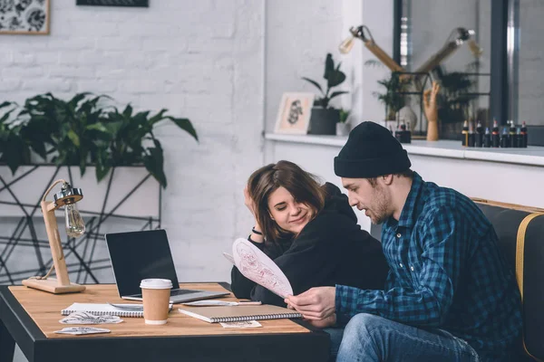 Young man and woman choosing tattoo design in studio — Stock Photo