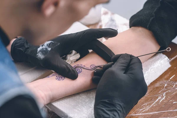 Artista masculino em luvas trabalhando no braço tatuagem peça em estúdio — Fotografia de Stock