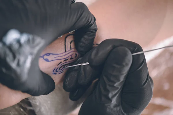 Vista de cerca del artista del tatuaje en guantes trabajando en la pieza del brazo - foto de stock