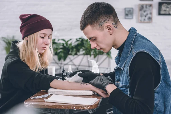 Girl and tattoo master during tattoo process in studio — Stock Photo