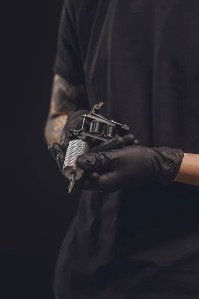 Máquina de tatuaje en manos masculinas aisladas en negro - foto de stock