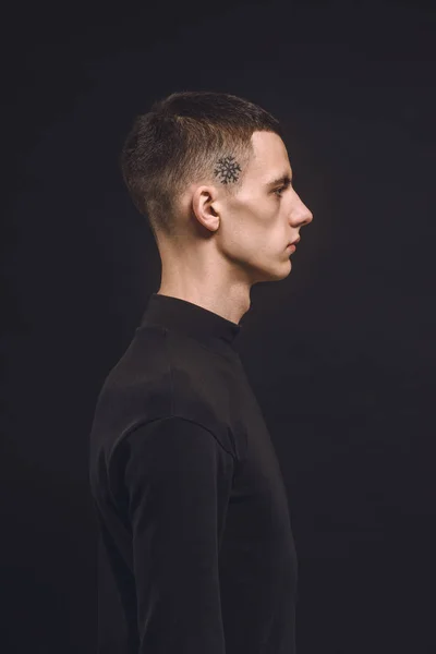 Young man with tattoo on temple isolated on black — Stock Photo