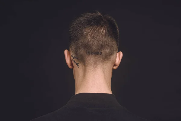 Вид сзади на татуировки на шее мужчины, изолированные на черном — стоковое фото