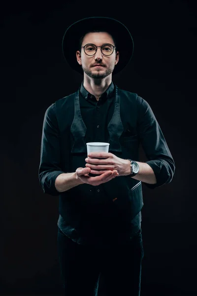 Homme en vêtements noirs tenant tasse de café isolé sur noir — Photo de stock