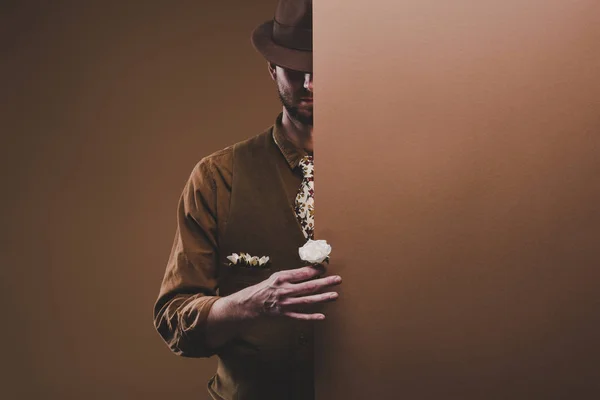 Man in stylish clothes holding rose flower isolated on brown — Stock Photo