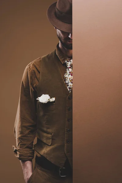 Молодой человек в винтажной одежде с бутоньеркой, изолированной на коричневом — стоковое фото