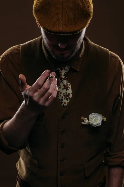 Jeune homme en vêtements vintage tenant la cigarette isolée sur brun — Photo de stock
