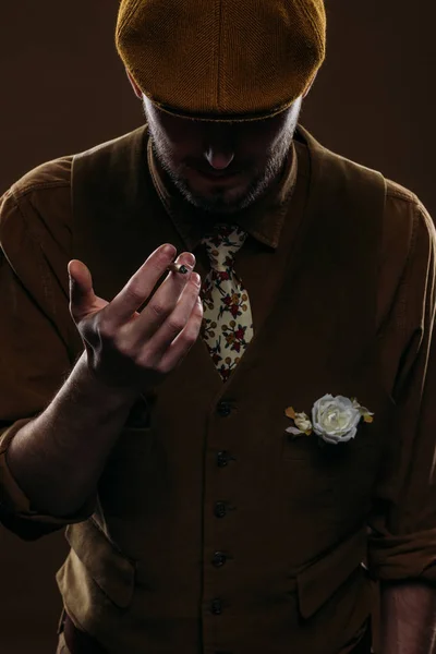 Young man in vintage styled clothes holding cigarette isolated on brown — Stock Photo