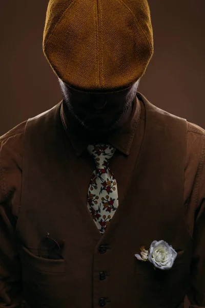 Чоловік у шнуровій жилеті та плоскій шапці ізольовані на коричневому — стокове фото