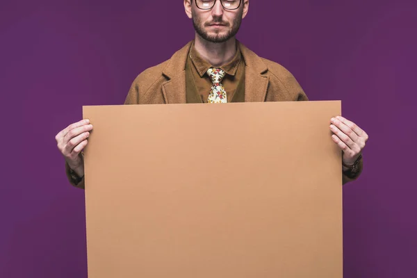 Homme élégant dans des vêtements de style vintage tenant le papier vide isolé sur violet — Photo de stock