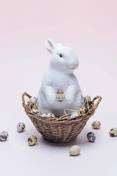 Coelho éster com ovos de codorna e palha em cesta no bege — Fotografia de Stock