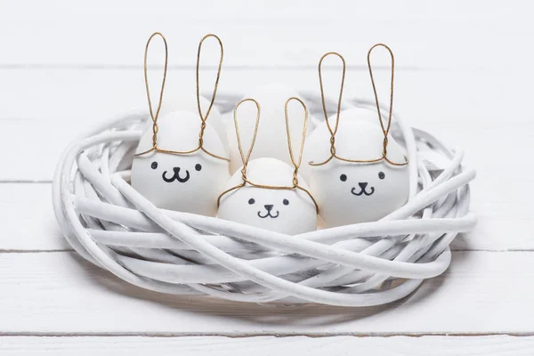 Huevos de pollo de Pascua con emoticonos y orejas de conejo en el nido - foto de stock