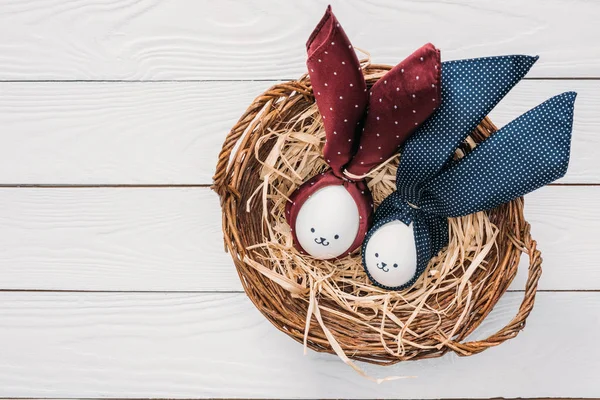 Top view of easter chicken eggs with smileys and bunny ears in nest — Stock Photo