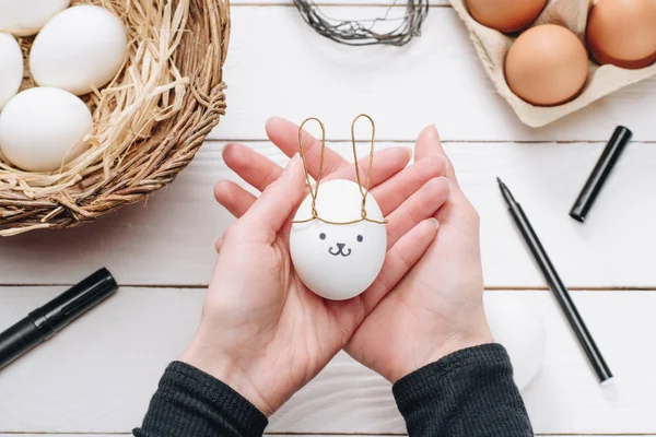 Image recadrée d'une femme tenant un oeuf de Pâques de poulet avec des oreilles de lapin et un sourire — Photo de stock