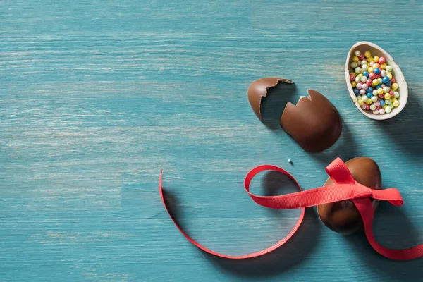 Vista superior de ovos de Páscoa de chocolate quebrados na mesa turquesa — Fotografia de Stock