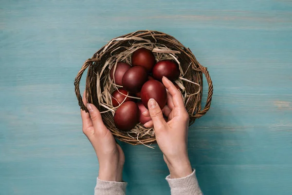 Cropped image of woman putting easter eggs in basket — Stock Photo