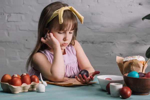 Adorable niño mirando pintado huevo de Pascua en la mano - foto de stock