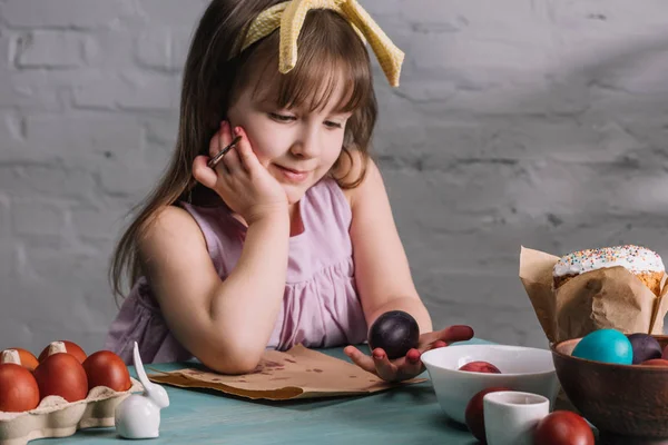 Adorable kid looking at painted egg in hand, easter concept — Stock Photo