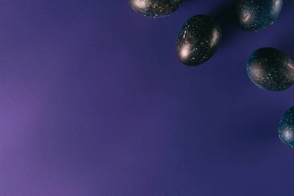 Vue de dessus des œufs de poulet peints sur la surface violette, concept de Pâques — Photo de stock