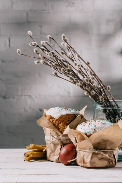 Пасхальный хлеб, кексы в банке и свечи на деревянном столе — стоковое фото