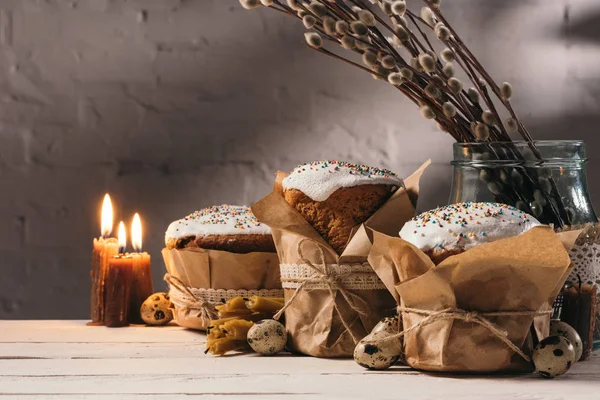 Easter bread, quail eggs and candles on wooden table — Stock Photo