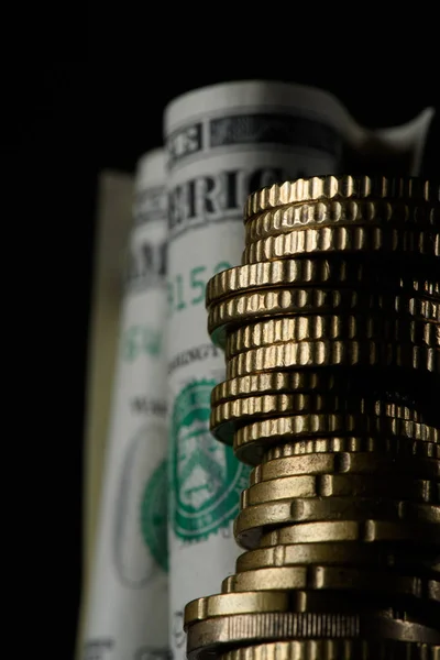 Selective focus of dollar banknotes and pile of coins isolated on black — Stock Photo