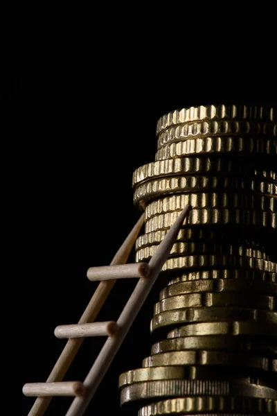 Vista ravvicinata di mucchio di monete con scaletta in legno isolata su nero — Foto stock