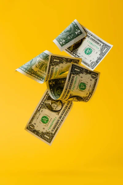 Close up view of falling dollar banknotes isolated on yellow — Stock Photo