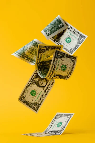Close up view of falling dollar banknotes isolated on yellow — Stock Photo