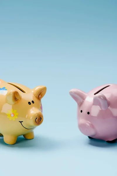 Vista de perto de dois bancos piggy amarelo e rosa isolados em azul — Fotografia de Stock