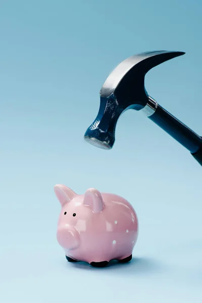 Vista de perto do banco piggy rosa e martelo isolado em azul — Fotografia de Stock