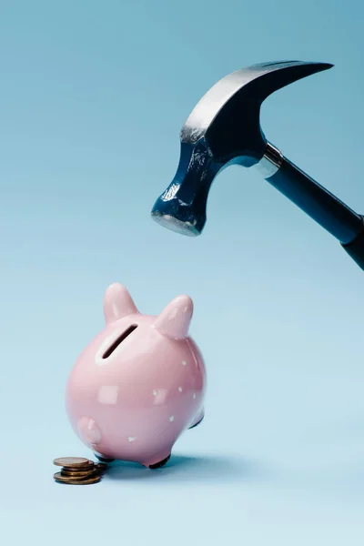 Close up view of pink piggy bank with stack of coins and hammer isolated on blue — Stock Photo