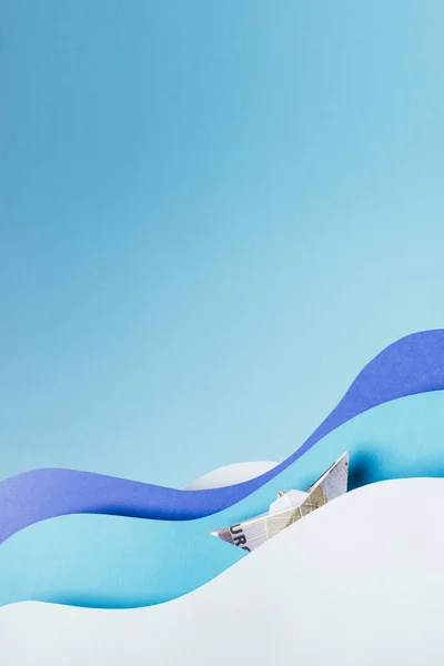 Vista de perto do navio feito de notas de euro navegando em ondas de papel azul isolado em azul — Fotografia de Stock