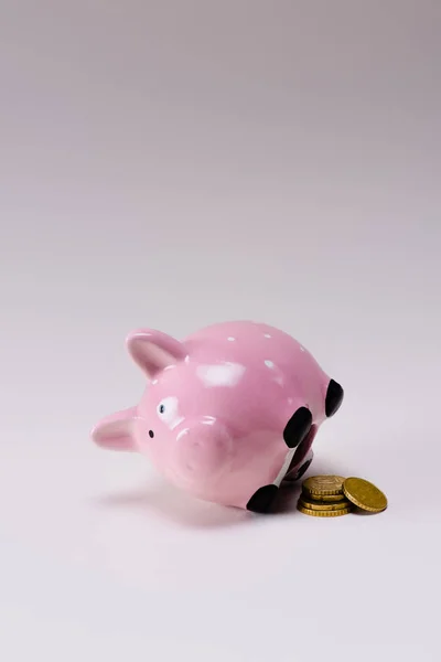 Close up view of pink piggy bank and pile of coins isolated on lilac — Stock Photo