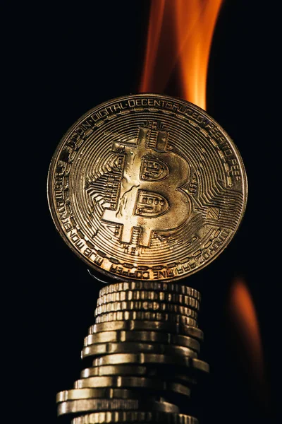 Vista de cerca de bitcoins dorados y fuego aislado en negro - foto de stock