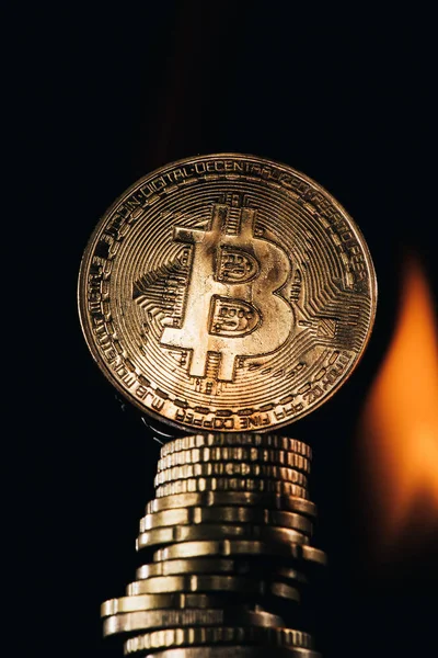 Крупним планом вид на золоті bitcoins і вогонь, ізольовані на чорному — стокове фото